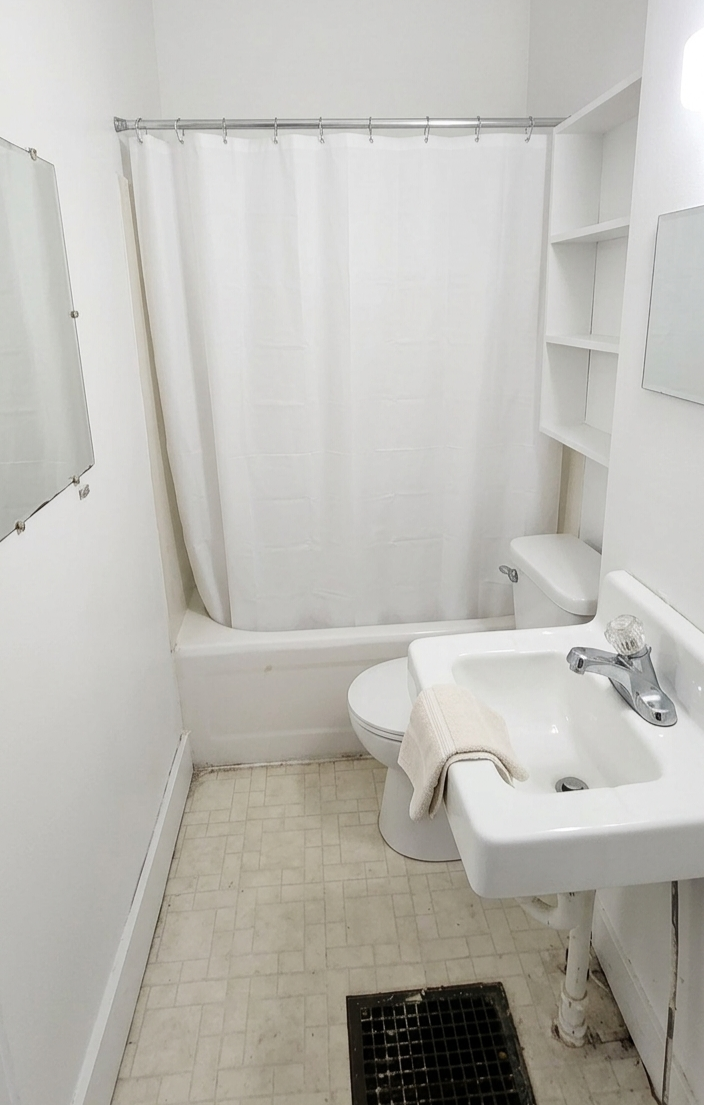 306 Unit 2 Bathroom — white bathroom with tub, sink, toilet, and wall shelving